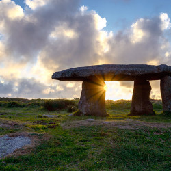 A starburst of sun gleaming through tLanyon Quoit an ancient neo